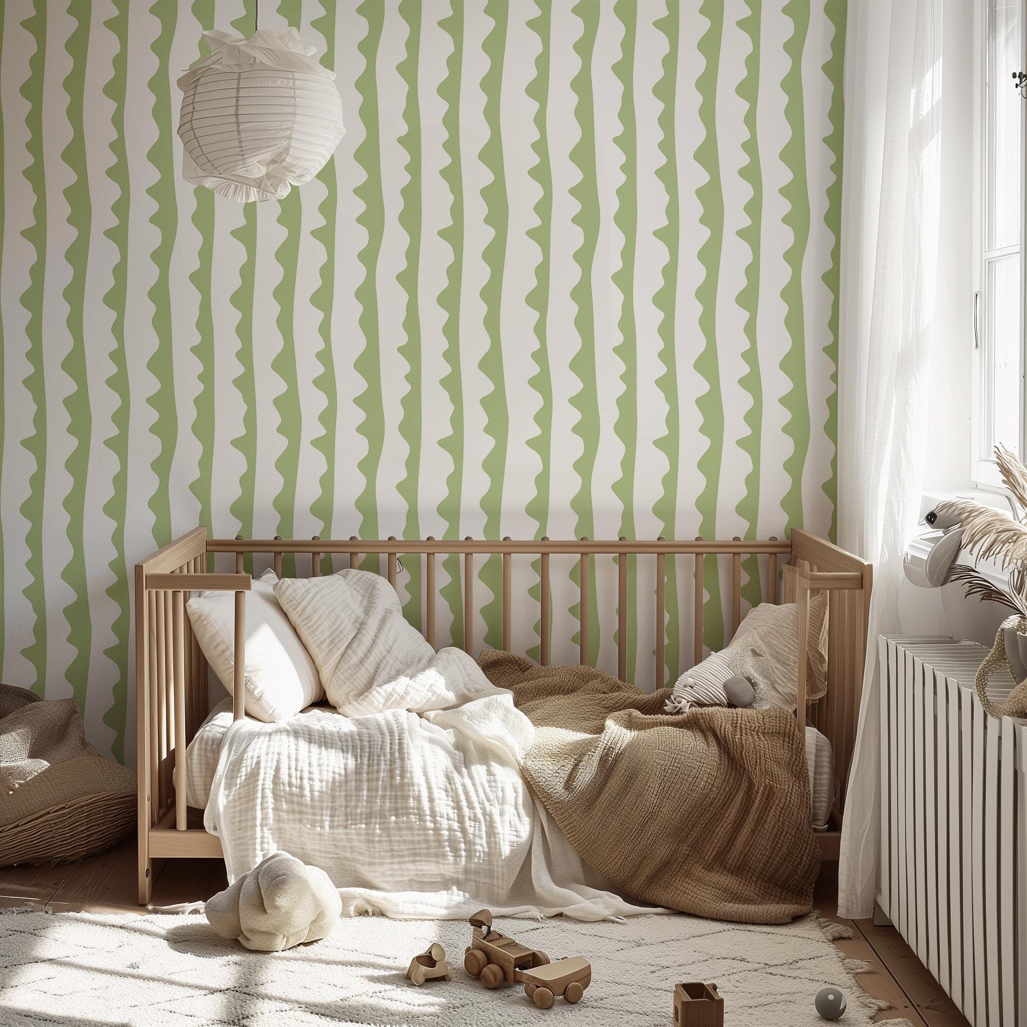 May include: A light wood crib with bedding, including pillows and a blanket, sits on a patterned rug. The room features a white and green striped wallpaper and a paper lantern. Wooden toy cars are on the rug.